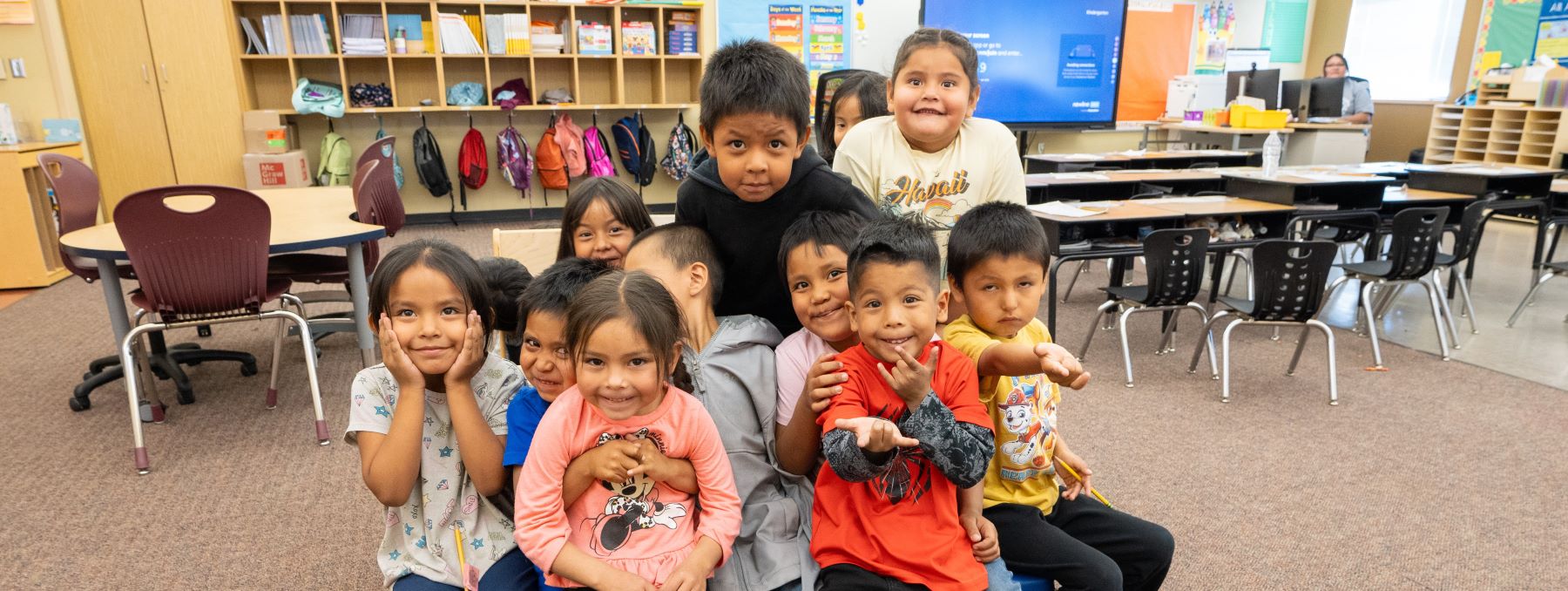 A group of students sitting in a group in a bright classroom.
