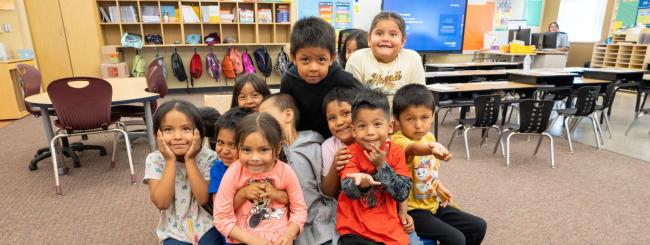 A group of students sitting in a group in a bright classroom.